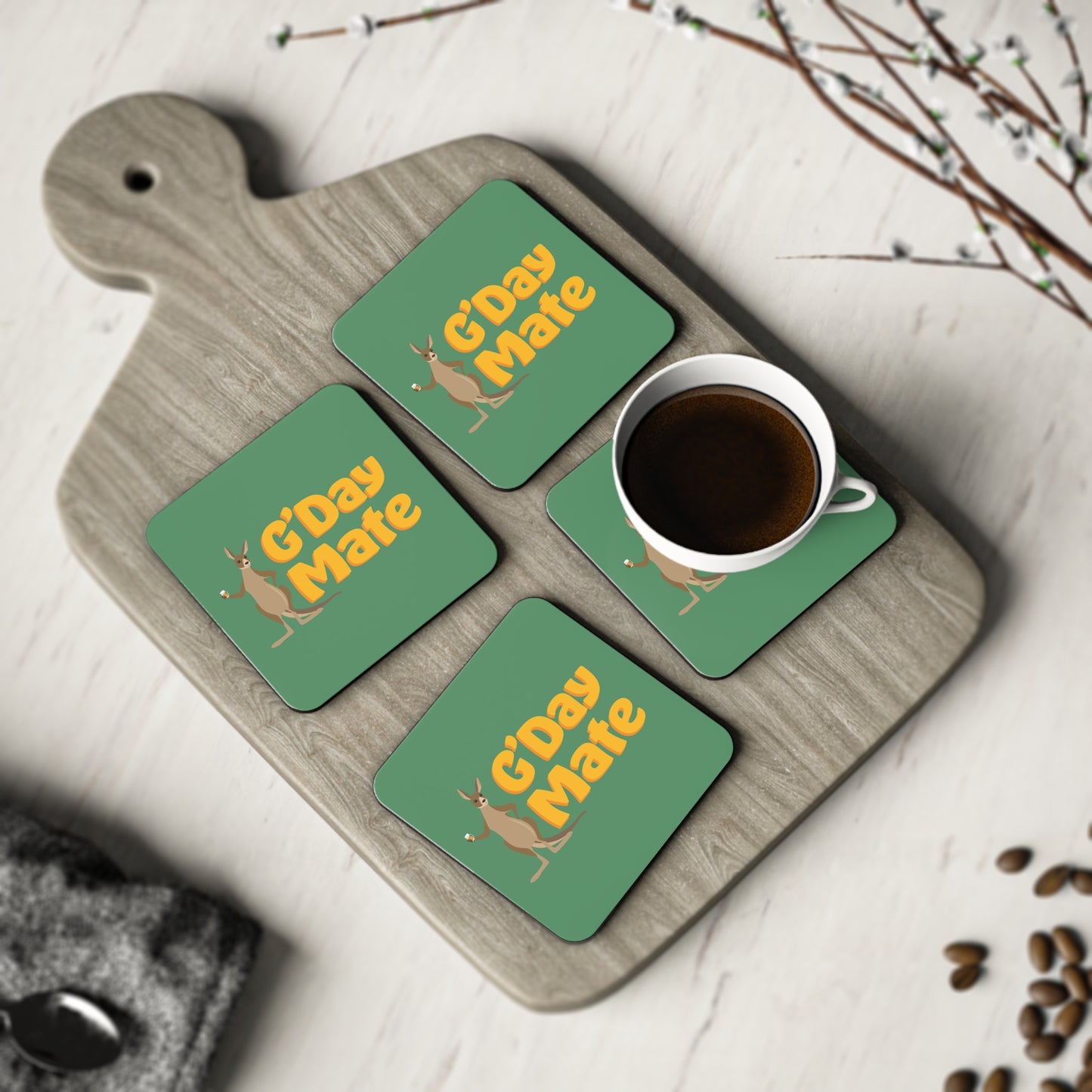 Set of four G'Day Mate coasters, green with yellow kangaroo print, styled on a wooden board with a coffee cup