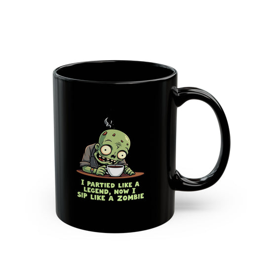 Black coffee mug with cartoon zombie sipping coffee and text 'I Partied Like a Legend, Now I Sip Like a Zombie'