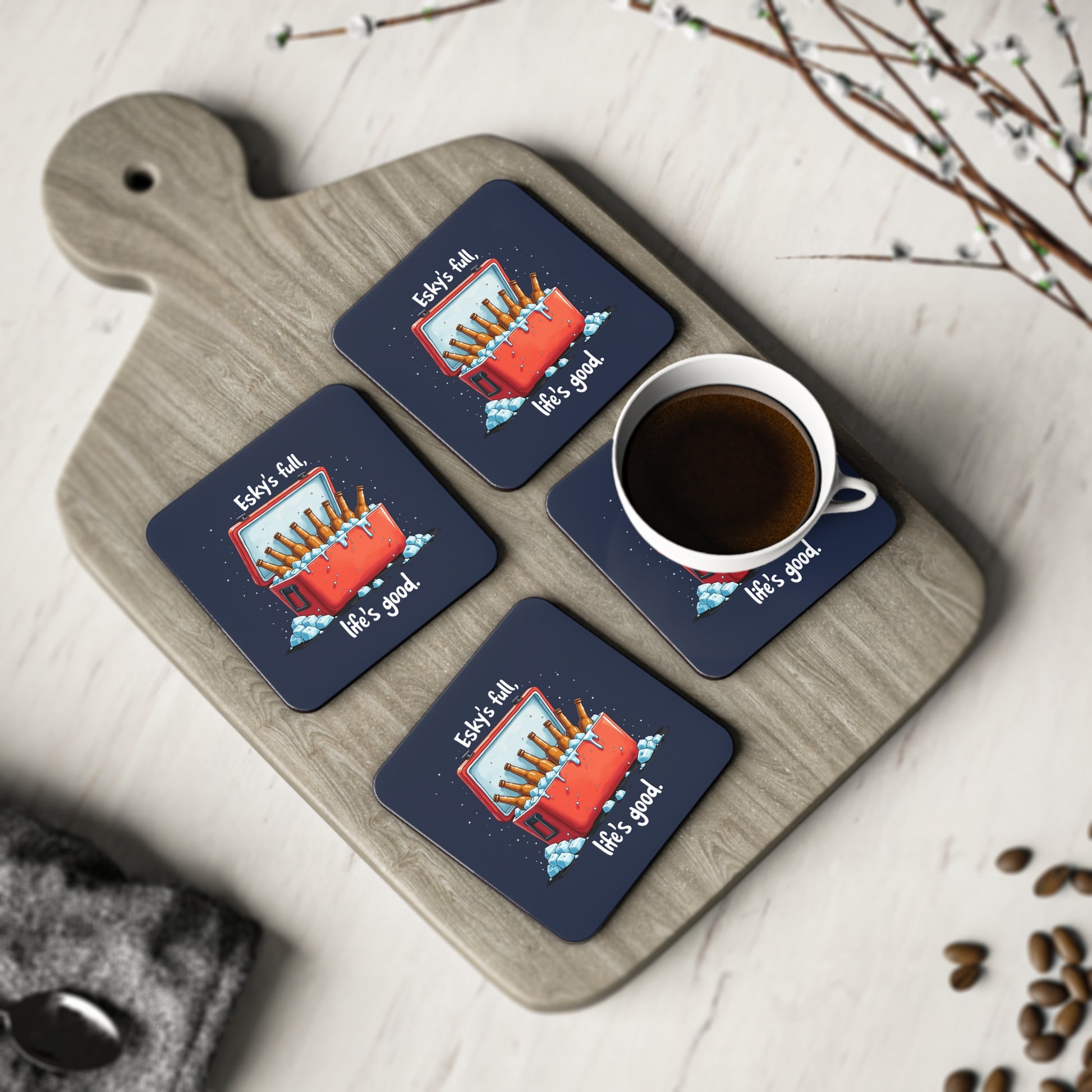 Set of 4 navy Esky's Full Coasters with red esky and beer bottles print, displayed on wooden board with coffee cup