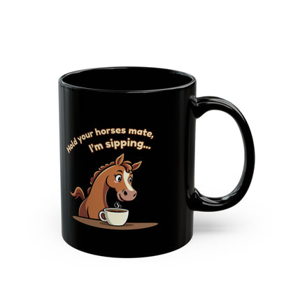Black coffee mug with cartoon horse sipping coffee and text 'Hold your horses mate, I'm sipping...'