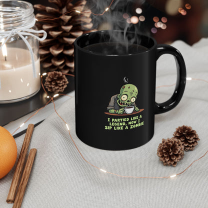 Black coffee mug with cartoon zombie and text 'I Partied Like A Legend, Now I Sip Like A Zombie'
