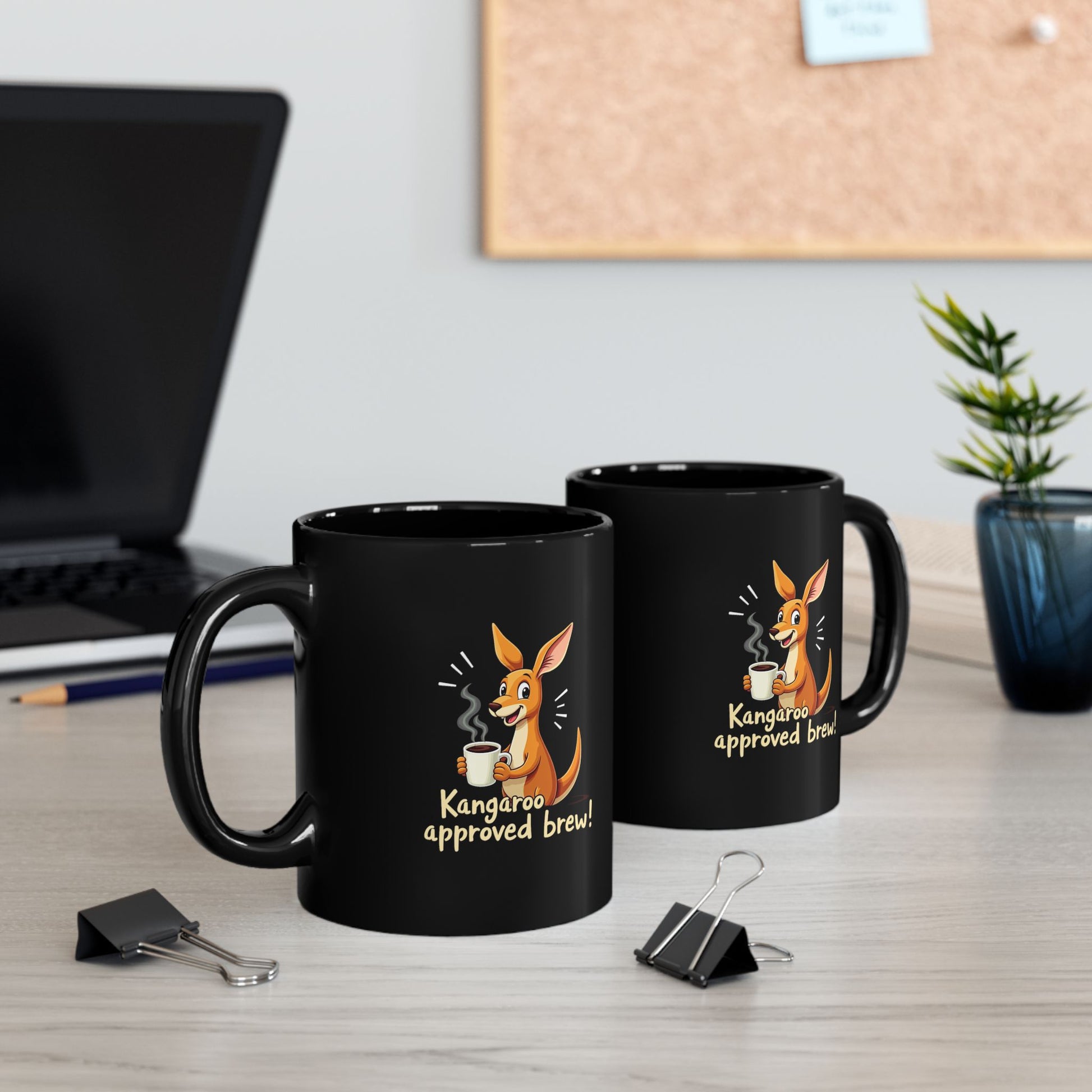 Black coffee mug with cartoon kangaroo holding a cuppa and 'Kangaroo approved brew!' text, shown on a desk