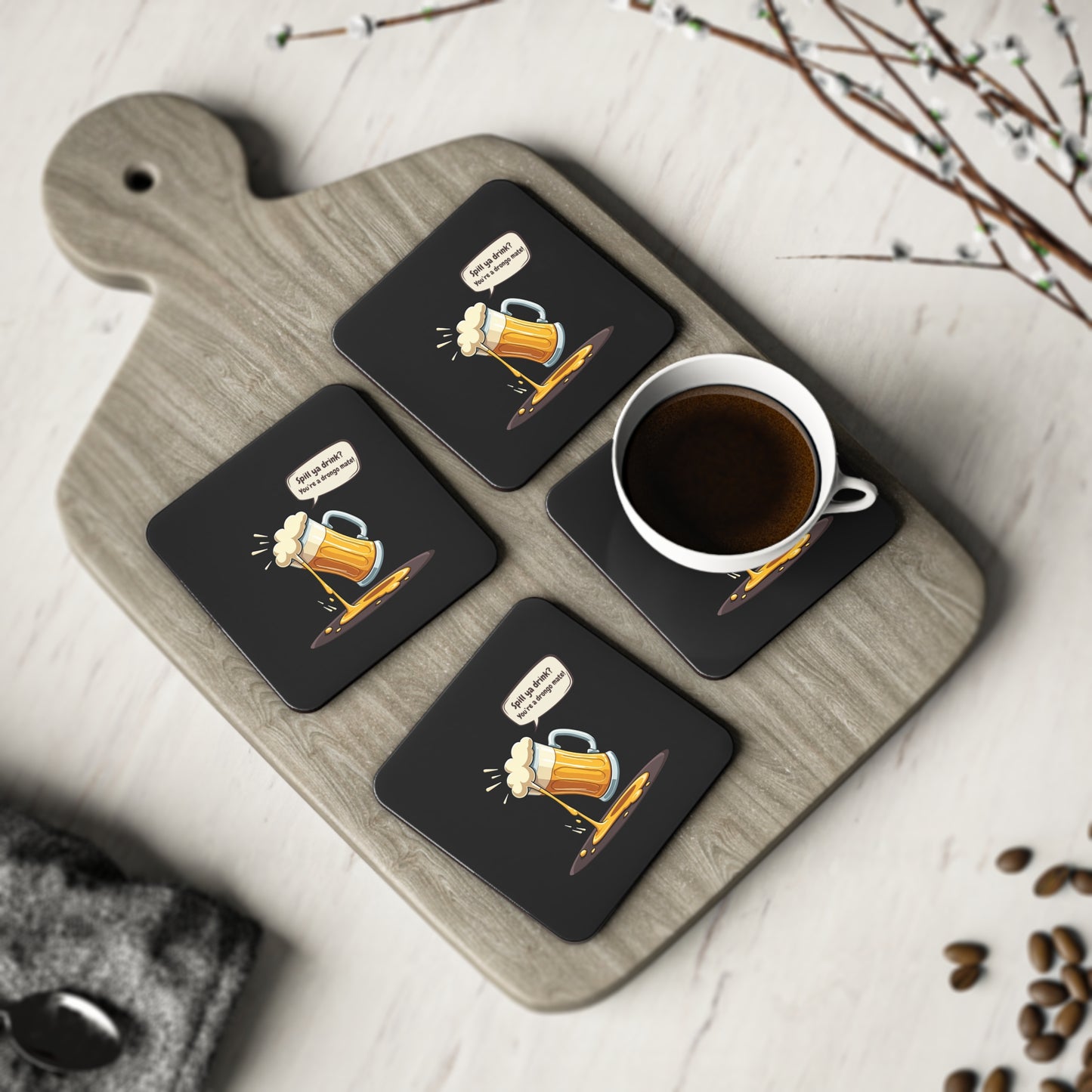 Spill Ya Beer Coasters set of 4, black with cartoon spilling beer mug graphic, displayed on timber board